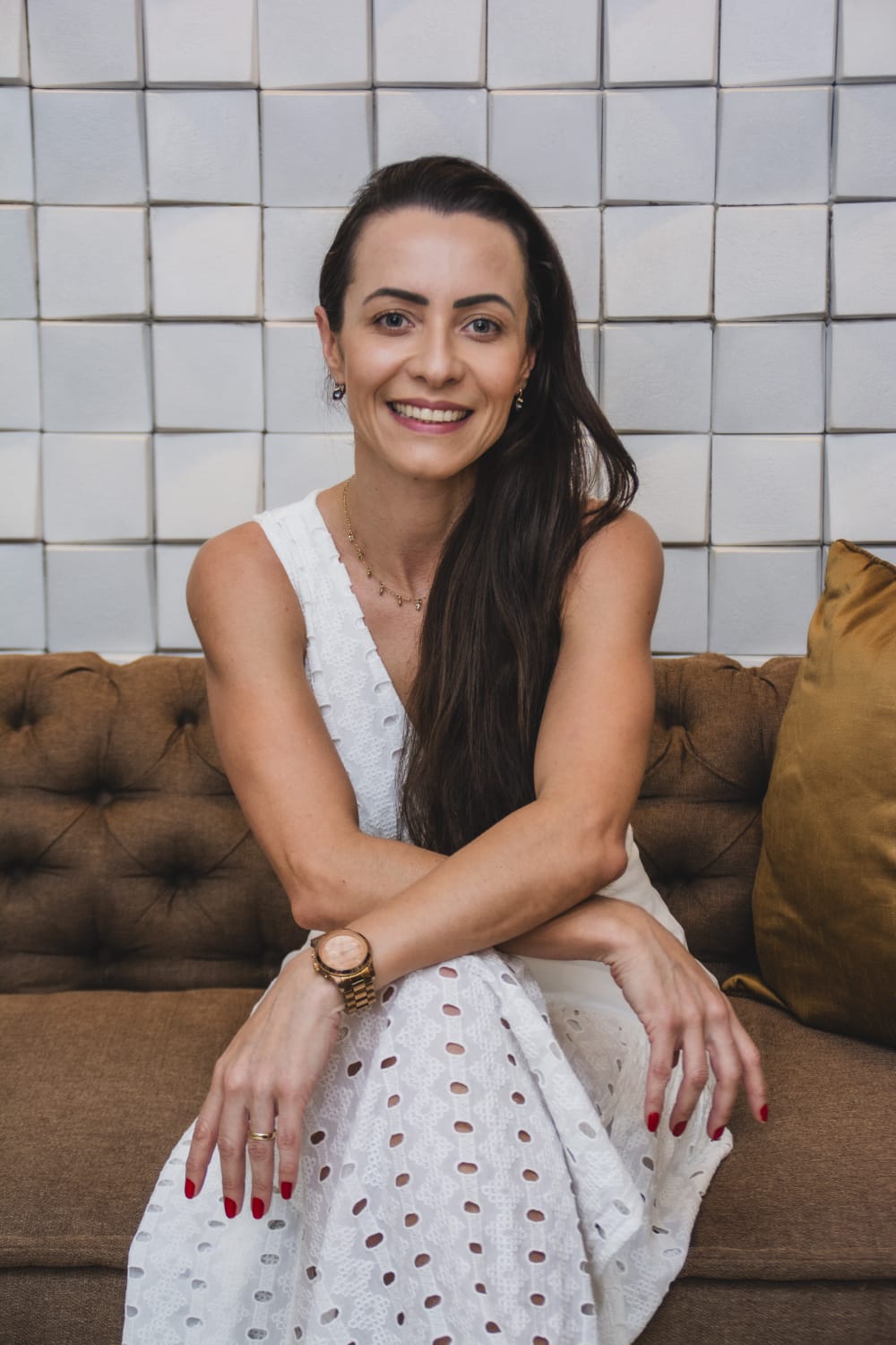 Keli Zeferino sorrindo, sentada em um sofá em ambiente acolhedor